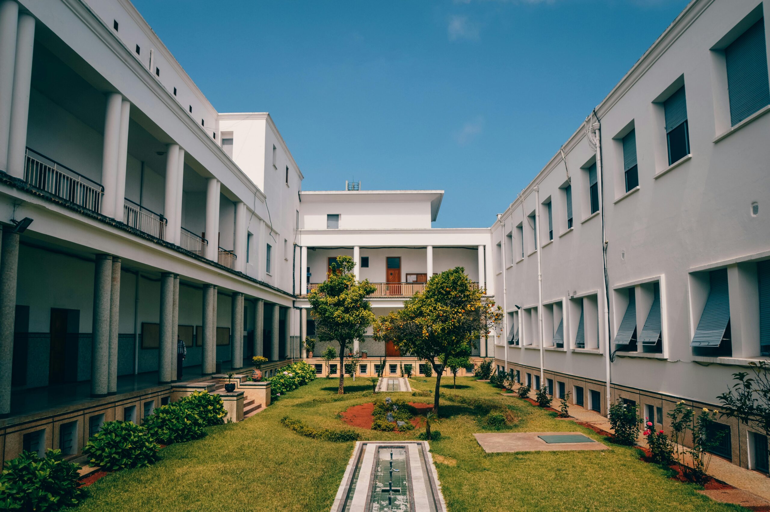 Elegant university building with garden courtyard in Rabat, Morocco under clear blue sky.